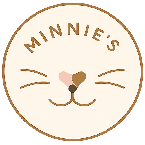A circular logo or label design featuring the text 'MINNIE'S' above a stylized cat face with whiskers, a pink heart-shaped nose, and a brown nose, all inside a tan circle on a white background.